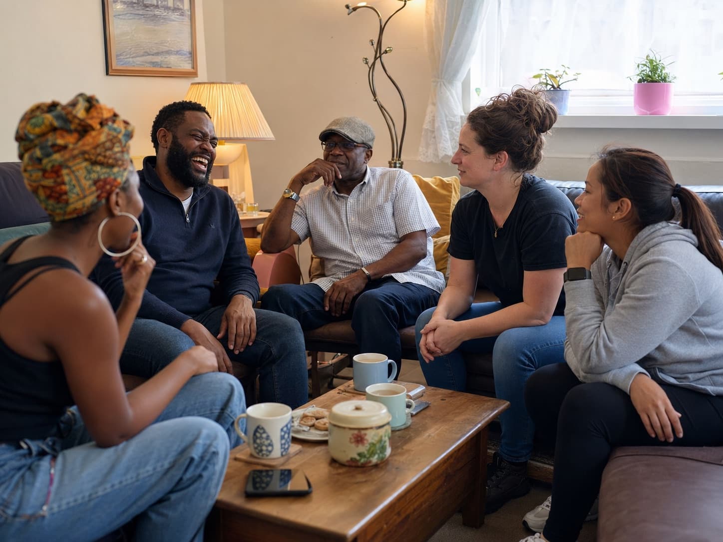 Members of the community chatting warmly over tea in a living room